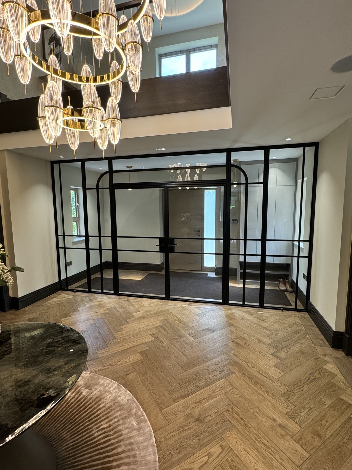 Bespoke steel entrance screen with arched detailing beside a herringbone oak floor