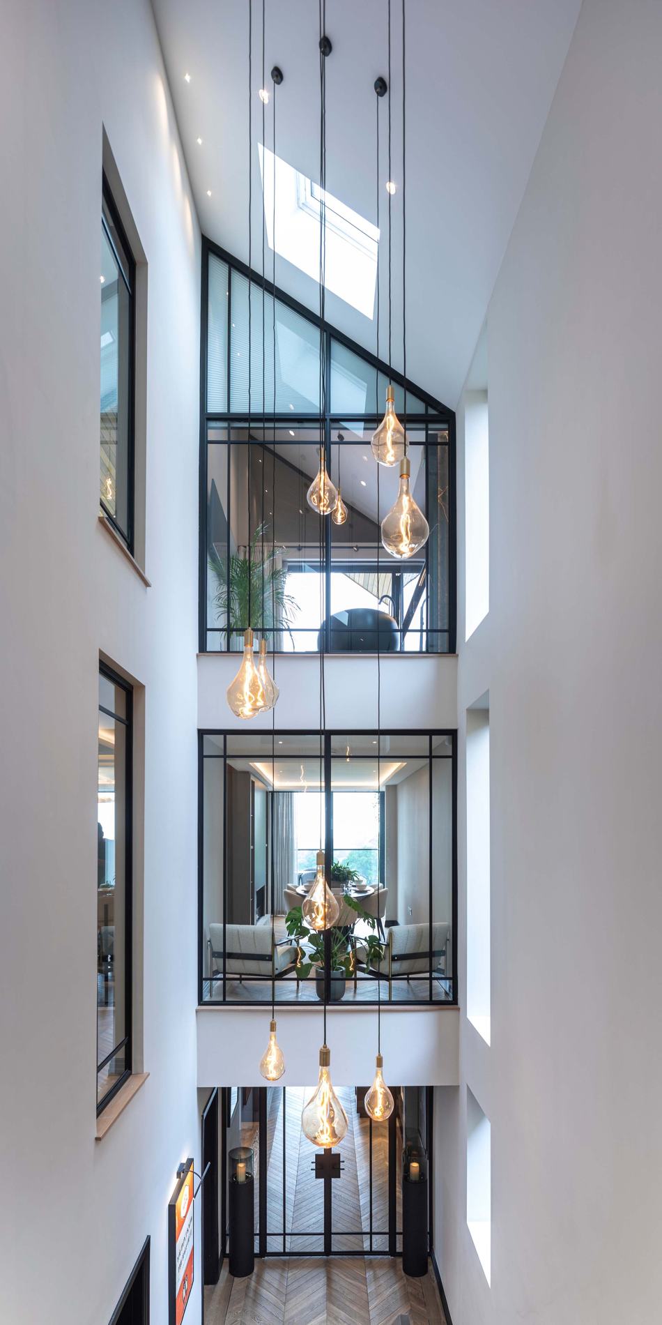 Three storeys of steel glazing in a full-height atrium with pendant filament bulbs