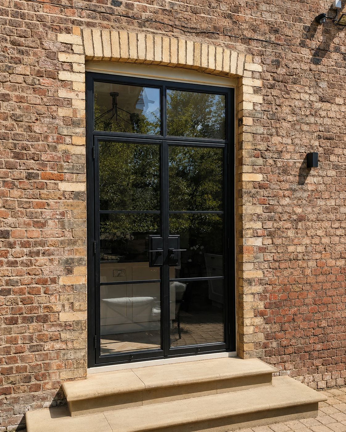 External steel doors with a brick arch head above stone steps