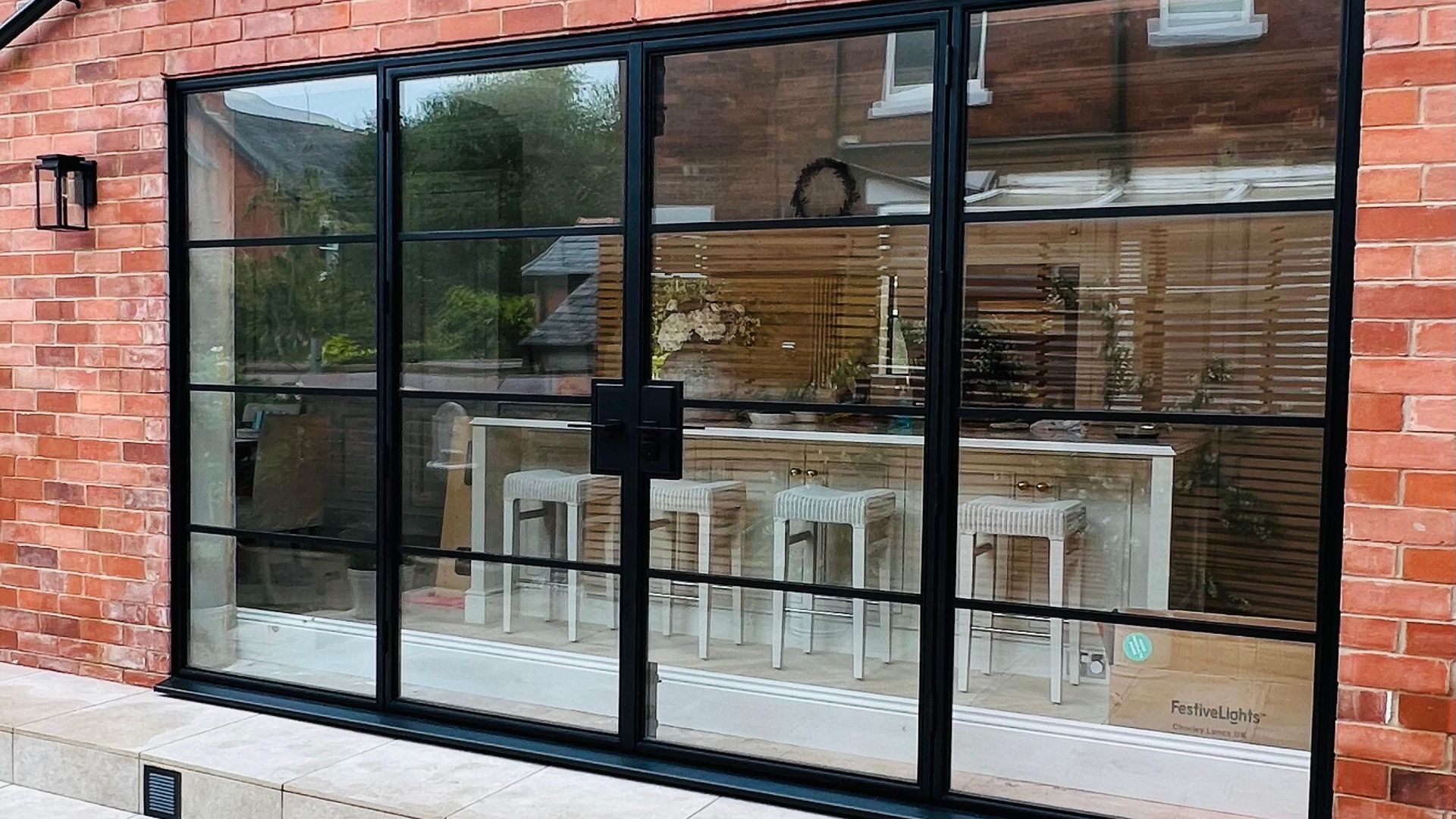 Bespoke steel external doors and screen in a red brick elevation onto a stone terrace
